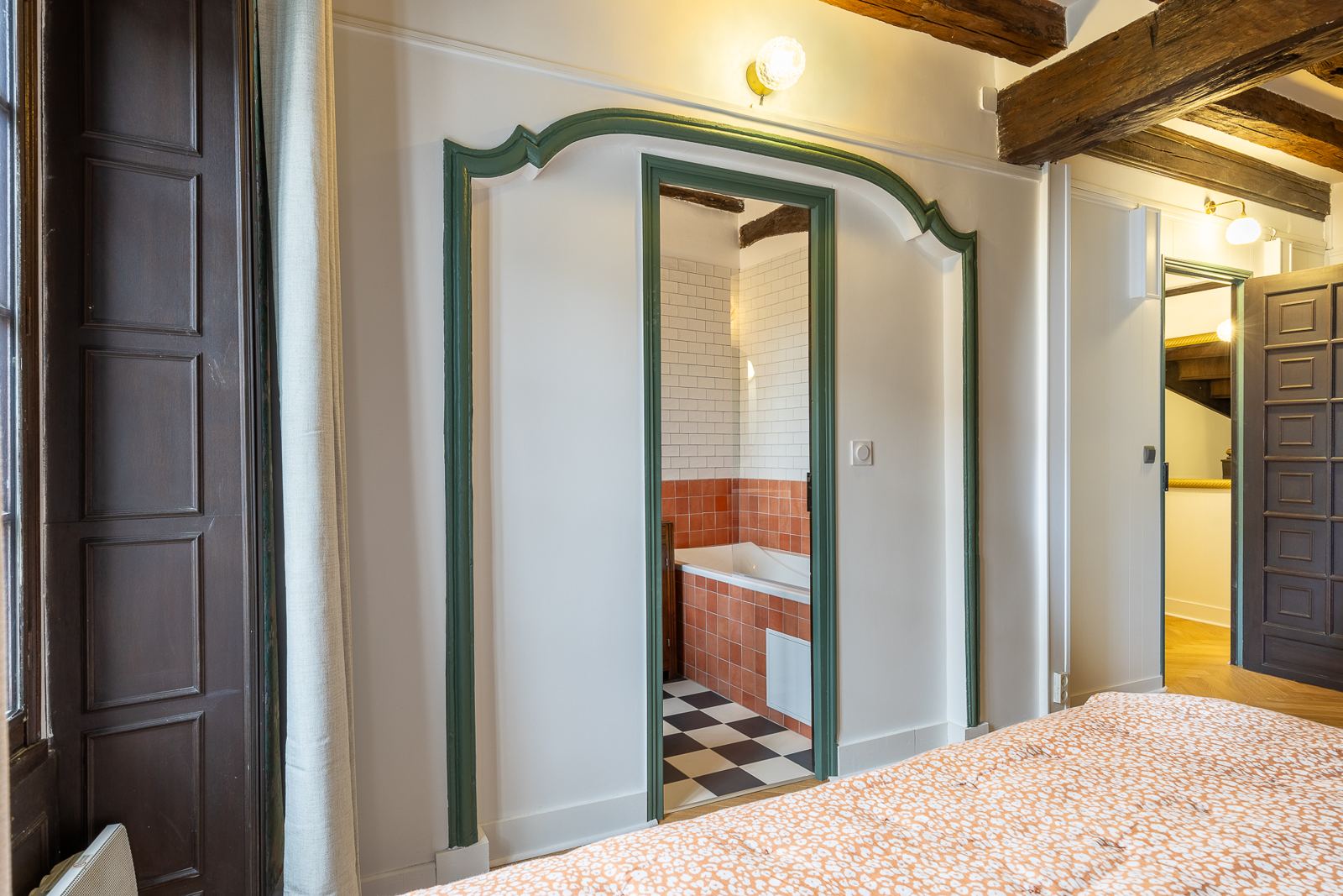 Encadrement de porte vert ouvrant sur la salle de bain au sol en damier