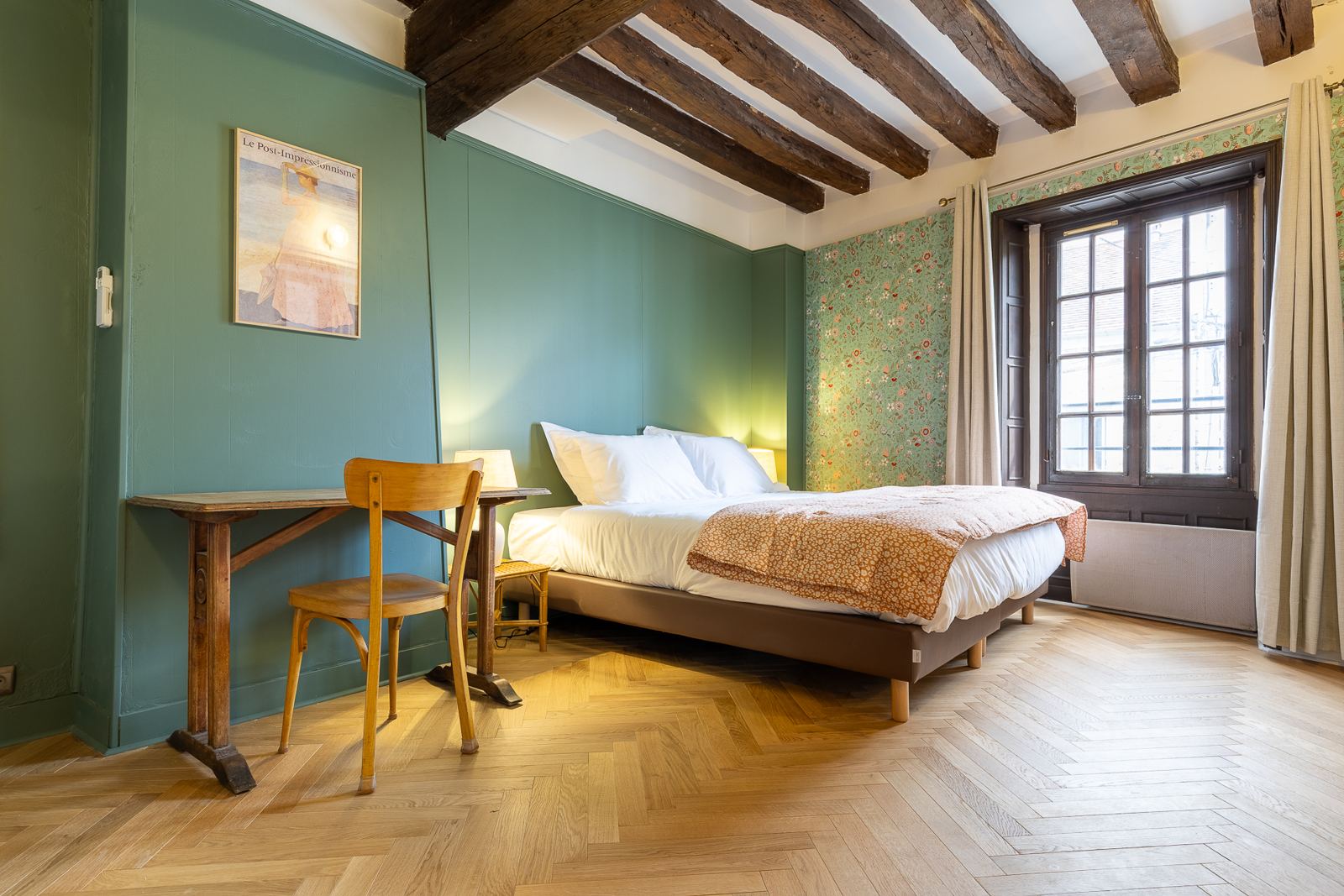 La chambre verte : poutres anciennes, lambris vert, papier peint fleuri, bureau ancien et grande fenêtre à petits carreaux